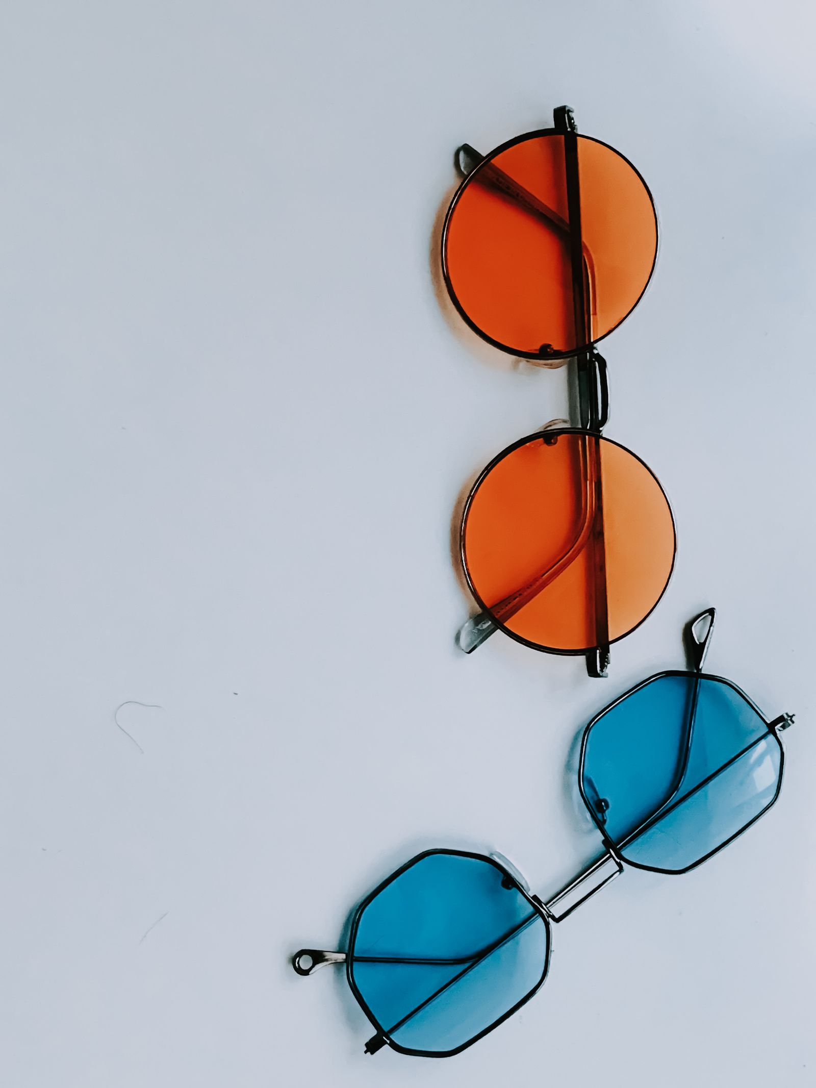 Oranje en blauwe zonnebrillen op een witte achtergrond