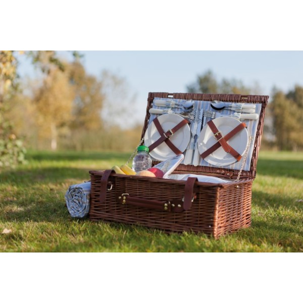 Rieten picknickmand met materiaal in. In een mooi veld tijdens goed weer.